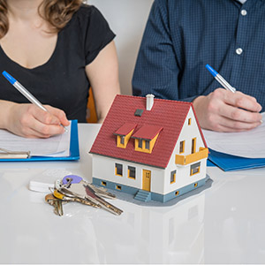 House model & keys; two people sign documents. Essential Texas real estate dispute resolution.